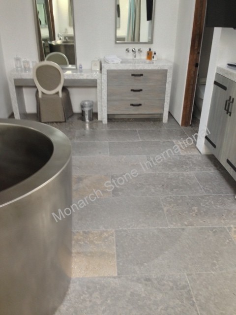 This is an example of a large traditional master bathroom in Orange County with grey cabinets, gray tile, stone tile, white walls, limestone floors and an integrated sink.