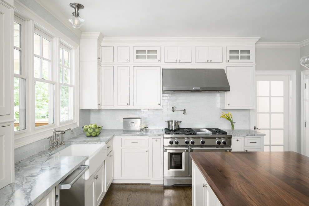 This is an example of a large transitional u-shaped open plan kitchen in Atlanta with with island, white cabinets, a farmhouse sink, shaker cabinets, marble benchtops, white splashback, subway tile splashback, stainless steel appliances and dark hardwood floors.