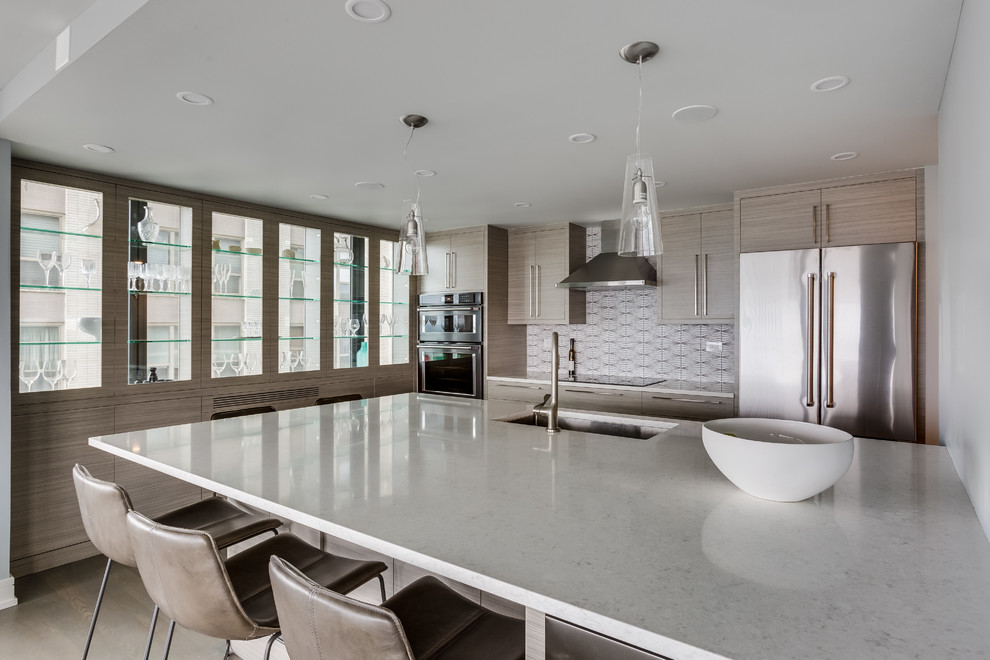 Mid-sized contemporary l-shaped open plan kitchen in Chicago with an undermount sink, flat-panel cabinets, light wood cabinets, quartzite benchtops, multi-coloured splashback, ceramic splashback, stainless steel appliances, medium hardwood floors, a peninsula, brown floor and white benchtop.