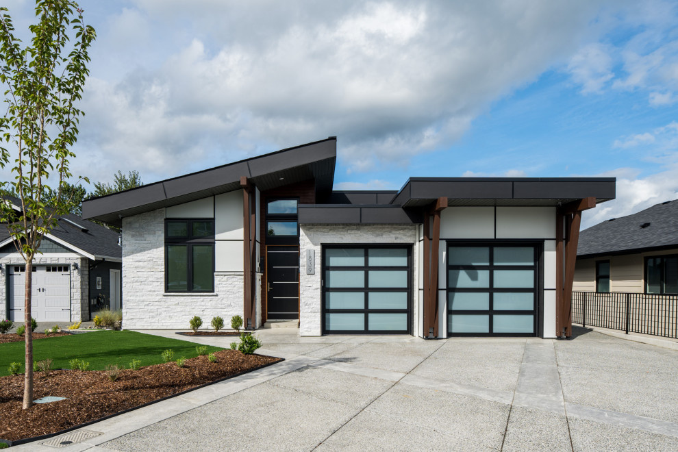 White contemporary two floor detached house in Vancouver with mixed cladding and board and batten cladding.