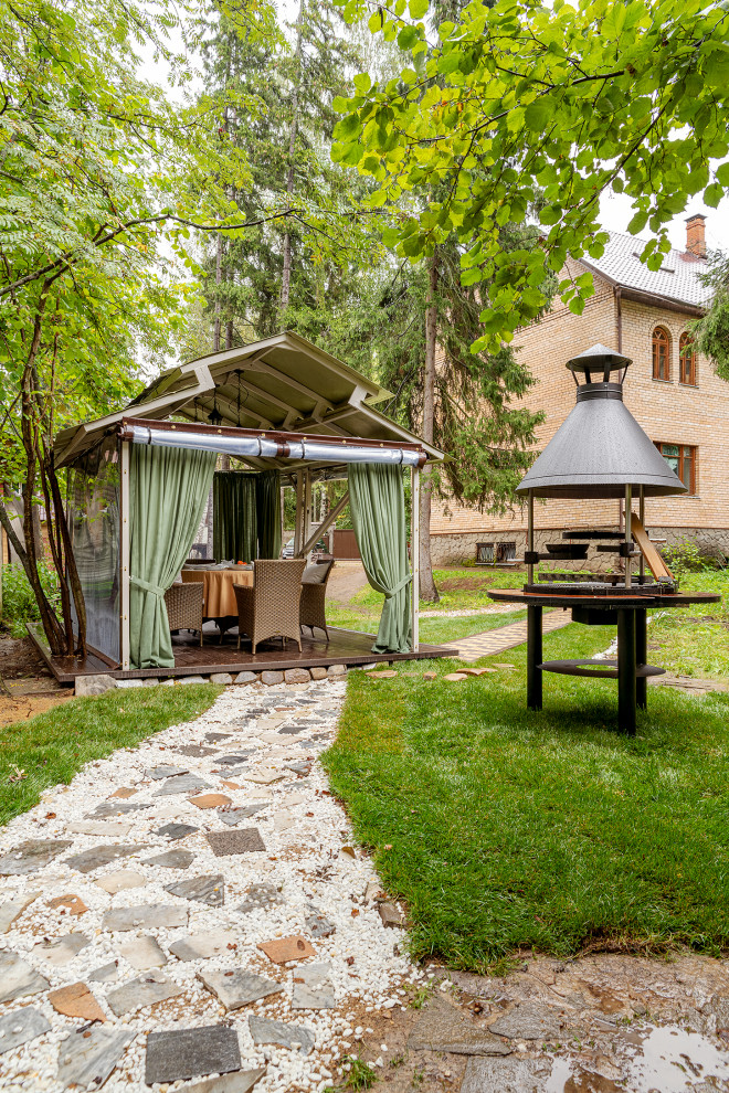 Imagen de patio actual de tamaño medio en patio trasero con cocina exterior, gravilla y cenador