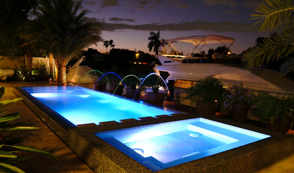 Pool house - mid-sized backyard stone and custom-shaped natural pool house idea in Miami