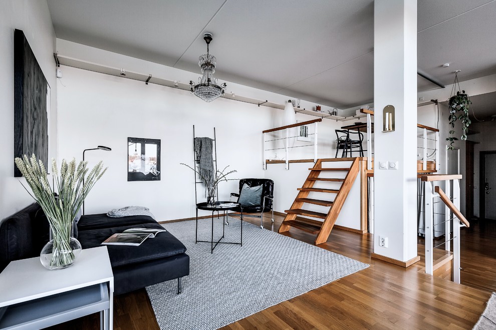 Scandinavian open concept living room in Stockholm with white walls, medium hardwood floors and brown floor.
