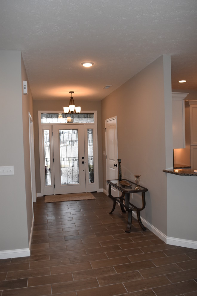 Example of a mid-sized transitional porcelain tile front door design with beige walls and a glass front door