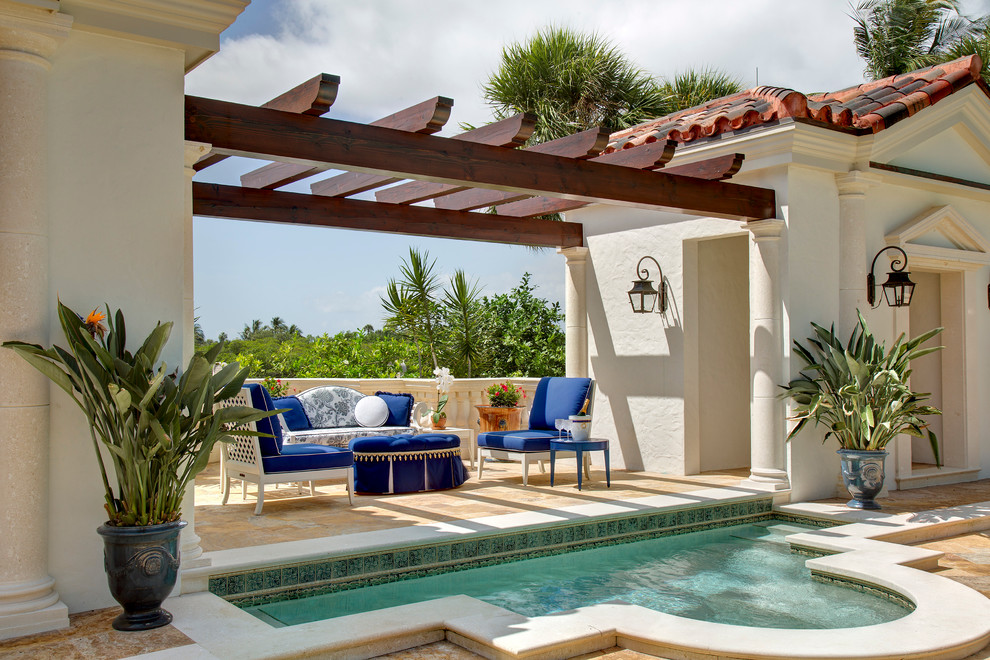 Large mediterranean backyard custom-shaped pool in Miami with natural stone pavers and a hot tub.