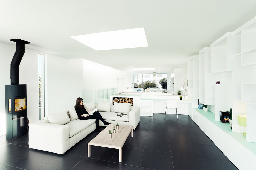 Inspiration for a contemporary open concept living room in Hampshire with white walls, a wood stove and black floor.