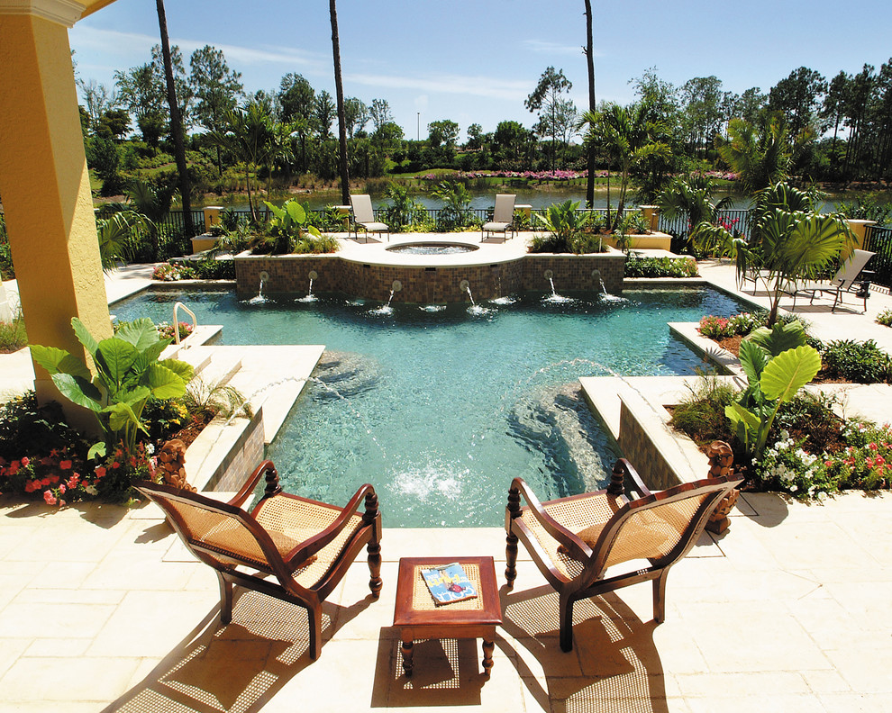 Design ideas for an expansive mediterranean backyard pool in Miami with a water feature and natural stone pavers.