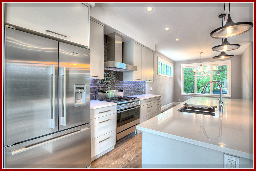 Open concept kitchen - mid-sized single-wall medium tone wood floor open concept kitchen idea in Calgary with a double-bowl sink, flat-panel cabinets, white cabinets, quartzite countertops, gray backsplash, glass tile backsplash, stainless steel appliances and an island