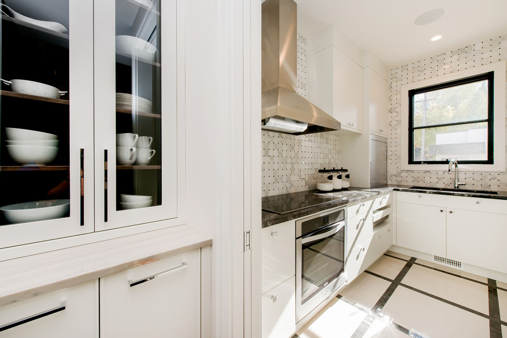 Kitchen pantry - large transitional l-shaped ceramic tile kitchen pantry idea in Calgary with a double-bowl sink, flat-panel cabinets, granite countertops, white backsplash, paneled appliances, an island and stone tile backsplash