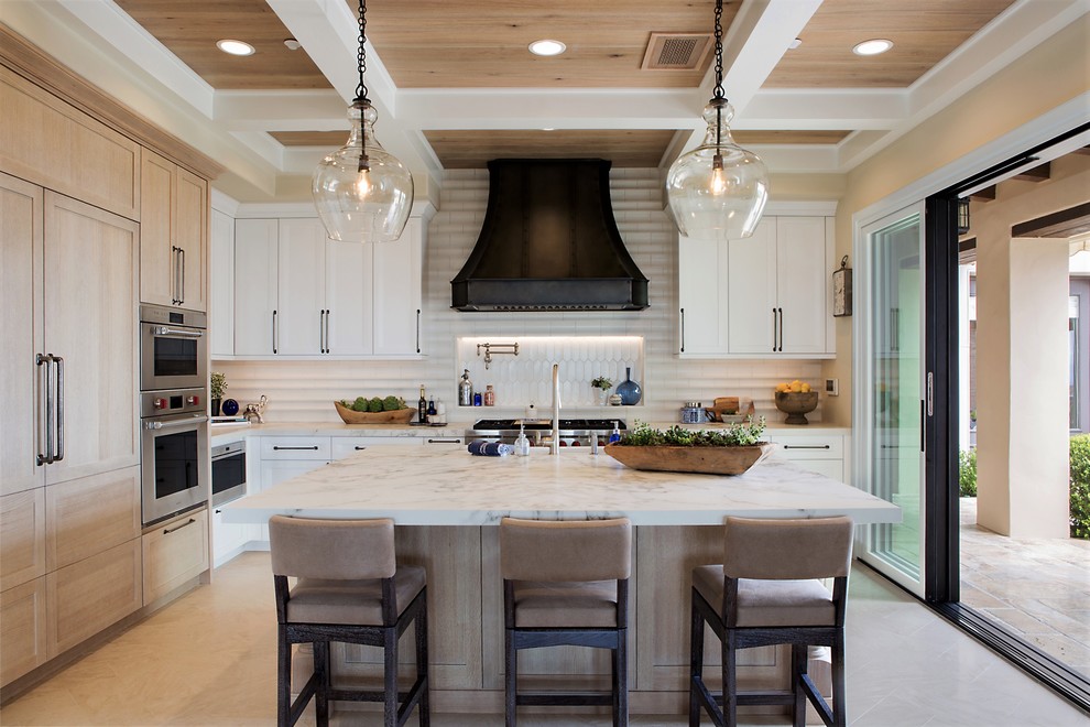 Photo of a large transitional l-shaped kitchen in Denver with recessed-panel cabinets, white cabinets, quartz benchtops, white splashback, ceramic splashback, panelled appliances, limestone floors, with island, beige floor and white benchtop.