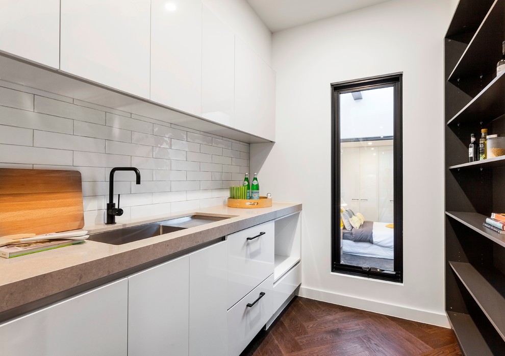 Photo of a large contemporary galley eat-in kitchen in Melbourne with an undermount sink, recessed-panel cabinets, white cabinets, quartz benchtops, grey splashback, stone slab splashback, black appliances, medium hardwood floors and with island.