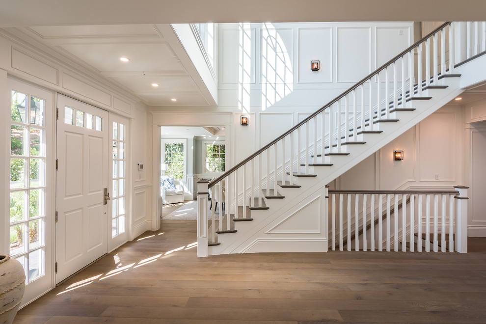 Design ideas for a large traditional foyer in Los Angeles with white walls, medium hardwood floors, a single front door, a white front door, coffered and decorative wall panelling.
