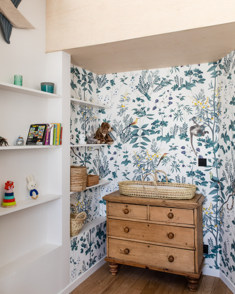 This is an example of a contemporary gender neutral nursery in Paris with white walls, light hardwood flooring, exposed beams and wallpapered walls.