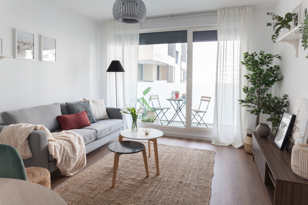 Design ideas for a mid-sized scandinavian open concept living room in Madrid with white walls, medium hardwood floors and brown floor.