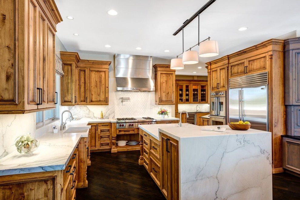 Large transitional u-shaped eat-in kitchen in Denver with an undermount sink, recessed-panel cabinets, light wood cabinets, marble benchtops, white splashback, stone slab splashback, stainless steel appliances, dark hardwood floors and with island.