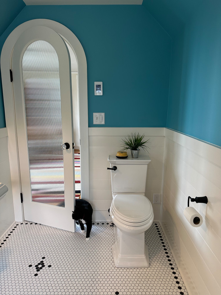Modelo de cuarto de baño único clásico renovado grande con bañera con patas, combinación de ducha y bañera, sanitario de dos piezas, paredes azules, suelo con mosaicos de baldosas, lavabo con pedestal, suelo blanco, ducha con cortina, hornacina y boiserie