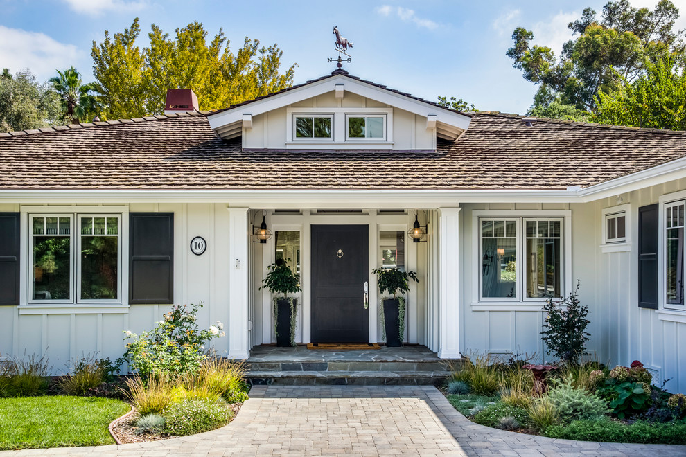 Photo of a large traditional one-storey white house exterior in Los Angeles with vinyl siding, a hip roof, a shingle roof, a grey roof and board and batten siding.