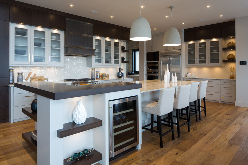 Large contemporary l-shaped eat-in kitchen in Calgary with with island, an undermount sink, flat-panel cabinets, dark wood cabinets, granite benchtops, white splashback, porcelain splashback, stainless steel appliances and medium hardwood floors.