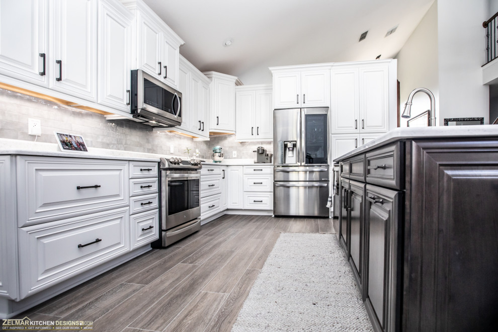Design ideas for a mid-sized transitional l-shaped eat-in kitchen in Orlando with an undermount sink, raised-panel cabinets, white cabinets, quartz benchtops, white splashback, ceramic splashback, porcelain floors, with island, brown floor and white benchtop.