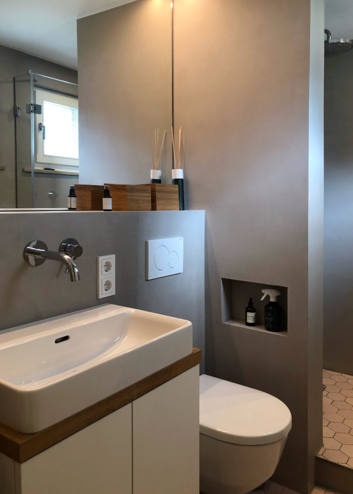 Inredning av ett modernt litet vit vitt badrum med dusch, med släta luckor, vita skåp, en öppen dusch, en vägghängd toalettstol, beige väggar, mosaikgolv, ett fristående handfat, rosa golv och med dusch som är öppen