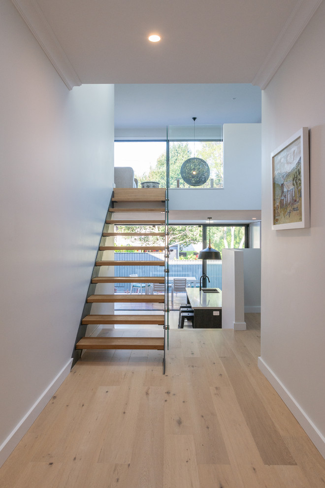 Mid-sized contemporary wood straight staircase in Sydney with glass railing and open risers.