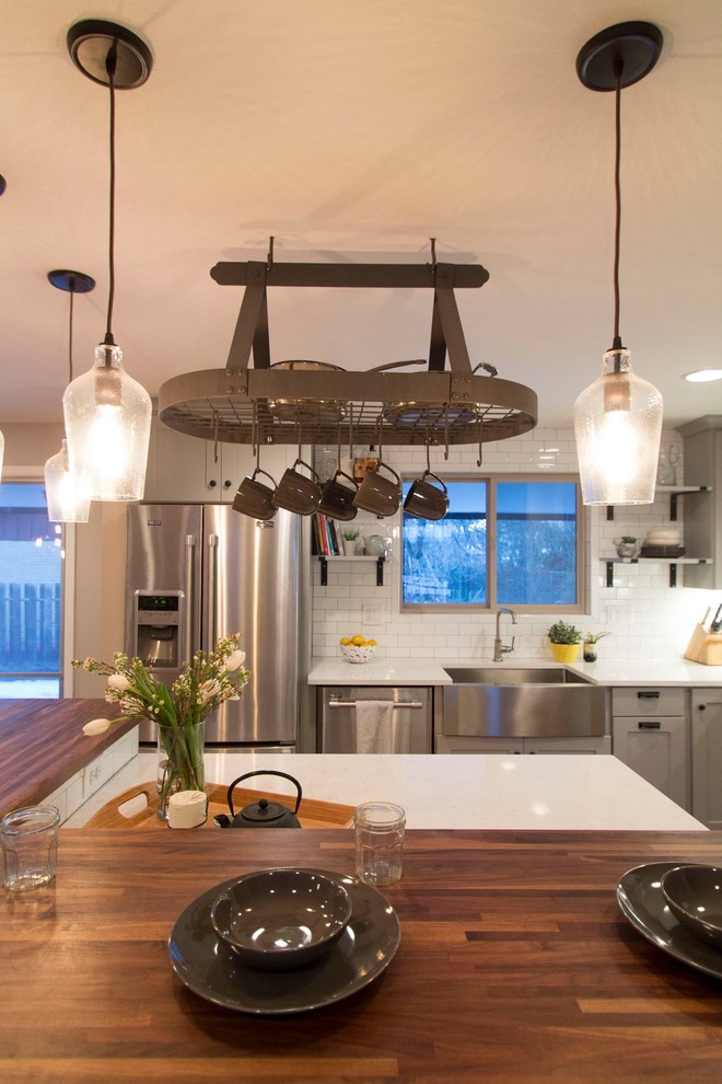 Mid-sized transitional l-shaped medium tone wood floor eat-in kitchen photo in Denver with a farmhouse sink, shaker cabinets, gray cabinets, quartz countertops, white backsplash, ceramic backsplash, stainless steel appliances and an island