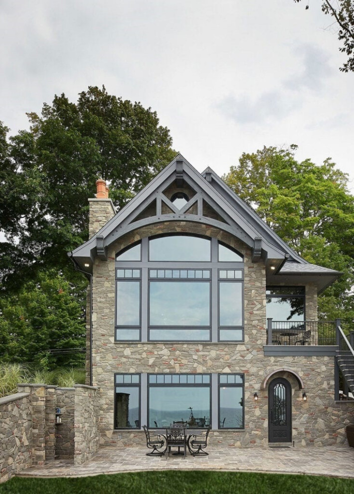 Inspiration for a traditional two-storey brown house exterior in Other with stone veneer, a shingle roof and a black roof.