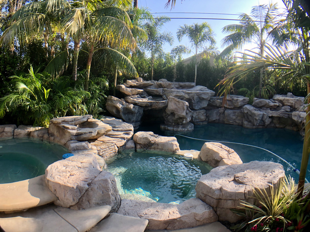 Large tropical backyard natural pool in Orange County with a water feature.