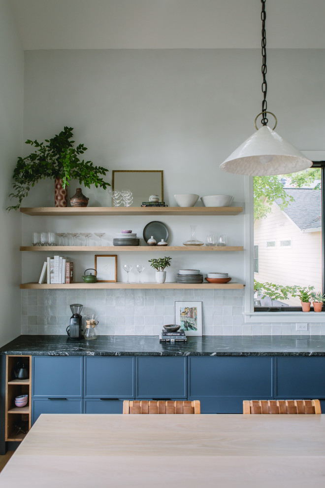 Medium sized scandi l-shaped kitchen/diner in Raleigh with a single-bowl sink, shaker cabinets, blue cabinets, granite worktops, white splashback, ceramic splashback, stainless steel appliances, light hardwood flooring, an island, yellow floors, black worktops and a vaulted ceiling.