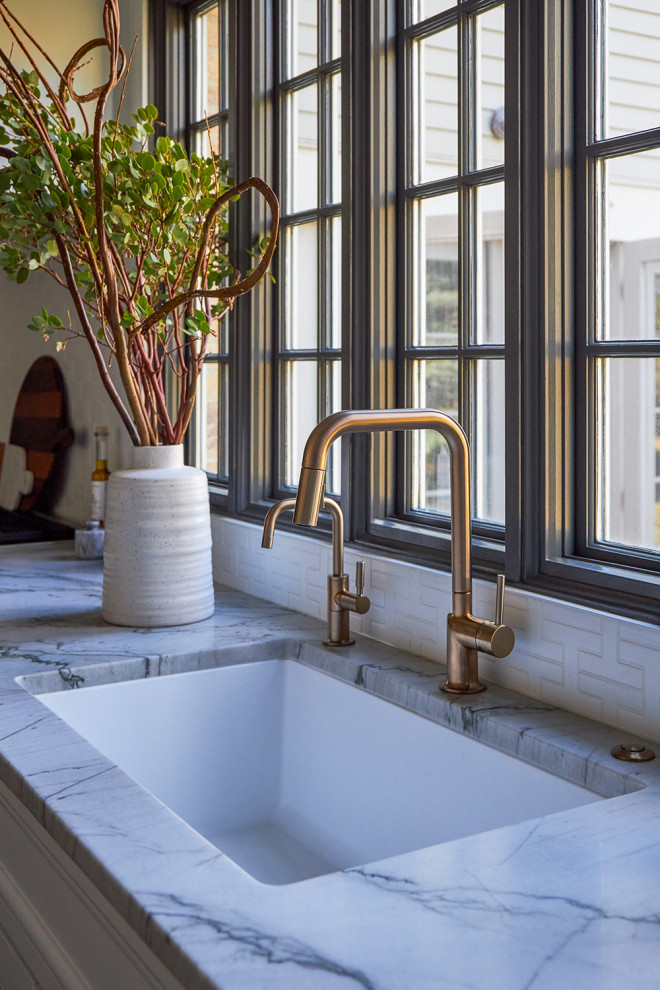 Mid-sized transitional galley medium tone wood floor enclosed kitchen photo in Chicago with a single-bowl sink, recessed-panel cabinets, white cabinets, quartzite countertops, white backsplash, ceramic backsplash, stainless steel appliances, an island and white countertops