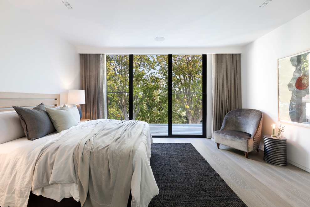 This is an example of a contemporary master bedroom in Melbourne with white walls, light hardwood floors and beige floor.