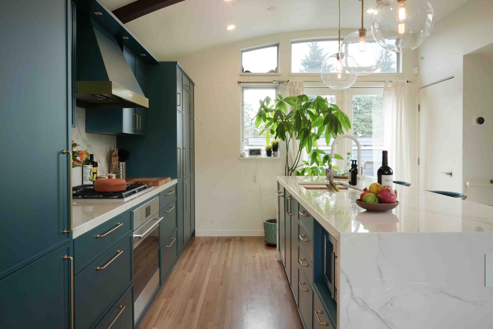 Photo of a mid-sized modern galley eat-in kitchen in Vancouver with a double-bowl sink, flat-panel cabinets, turquoise cabinets, marble benchtops, white splashback, marble splashback, panelled appliances, light hardwood floors, with island, beige floor, white benchtop and wood.