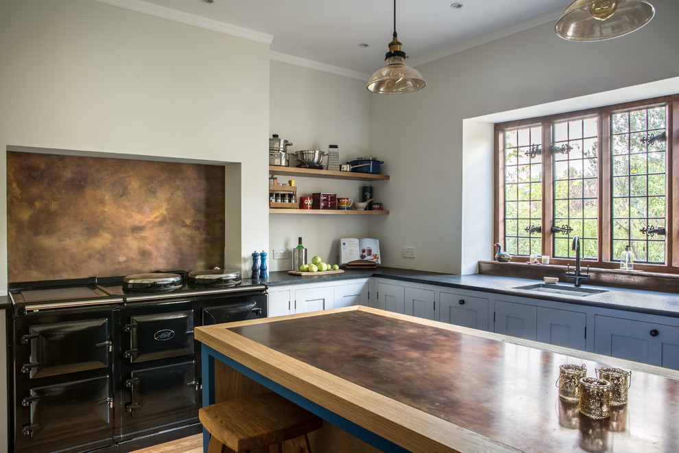Inspiration for a large country u-shaped eat-in kitchen in Other with shaker cabinets, grey cabinets, granite benchtops, black appliances, with island, an undermount sink, metallic splashback, metal splashback and light hardwood floors.