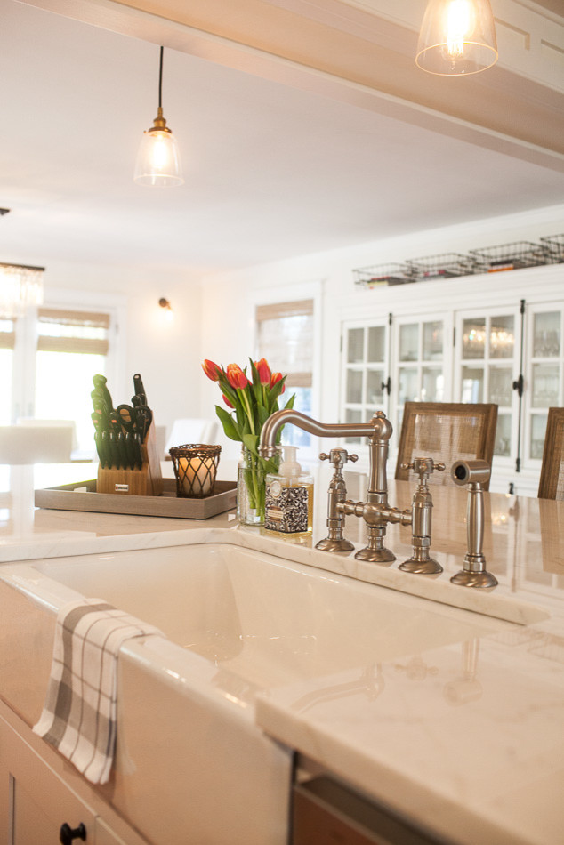 Inspiration for a large transitional medium tone wood floor eat-in kitchen remodel in St Louis with a farmhouse sink, flat-panel cabinets, white cabinets, an island, white backsplash, subway tile backsplash and stainless steel appliances