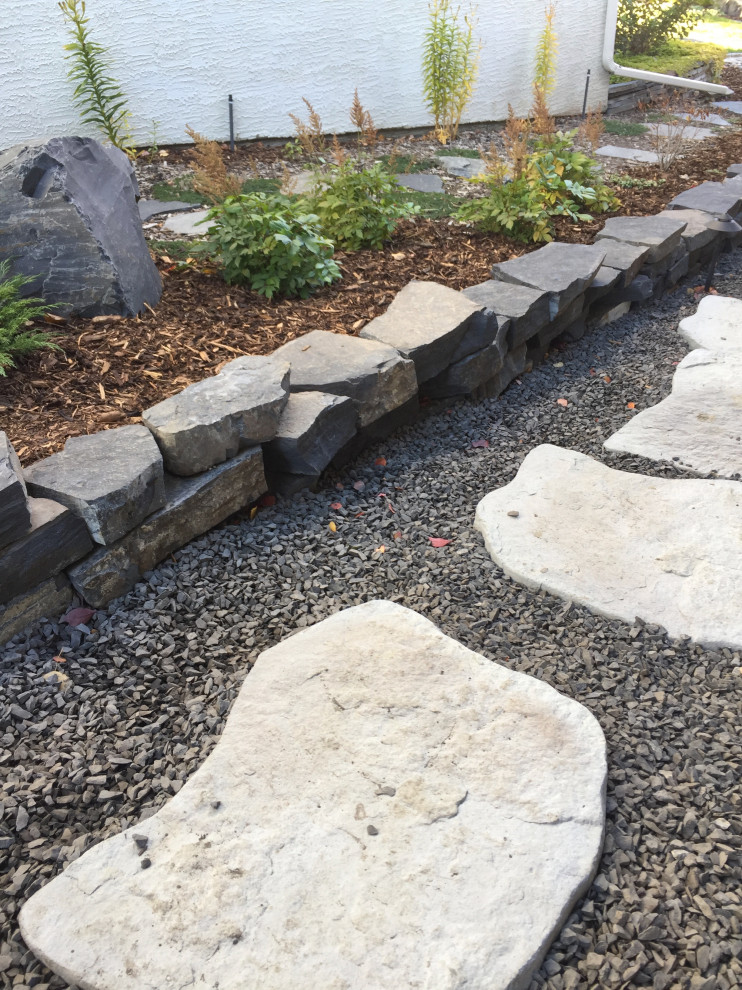 This is an example of a mid-sized sloped garden in Calgary with with path and decomposed granite.