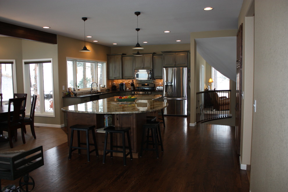 Example of a transitional eat-in kitchen design in Denver with an undermount sink, raised-panel cabinets, green cabinets, granite countertops, black backsplash and stainless steel appliances