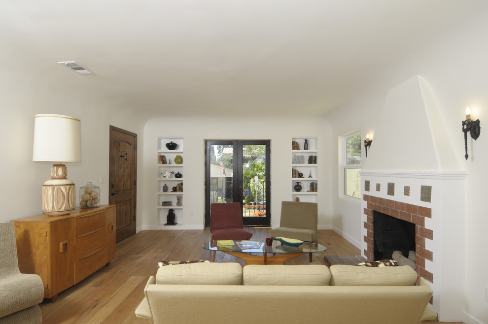 Photo of a mid-sized mediterranean formal open concept living room in Los Angeles with white walls, medium hardwood floors, a standard fireplace and a brick fireplace surround.