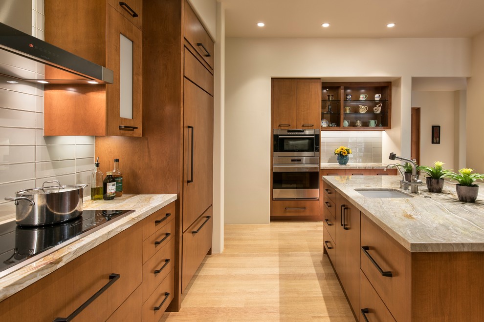 Inspiration for a contemporary u-shaped kitchen remodel in Phoenix with flat-panel cabinets, medium tone wood cabinets, white backsplash, stainless steel appliances, an island and a drop-in sink