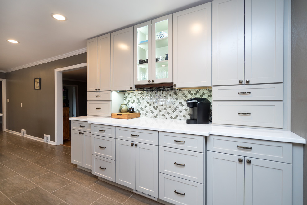 Open concept kitchen - mid-sized transitional l-shaped laminate floor open concept kitchen idea in DC Metro with a farmhouse sink, shaker cabinets, white cabinets, quartz countertops, gray backsplash, porcelain backsplash, stainless steel appliances and a peninsula