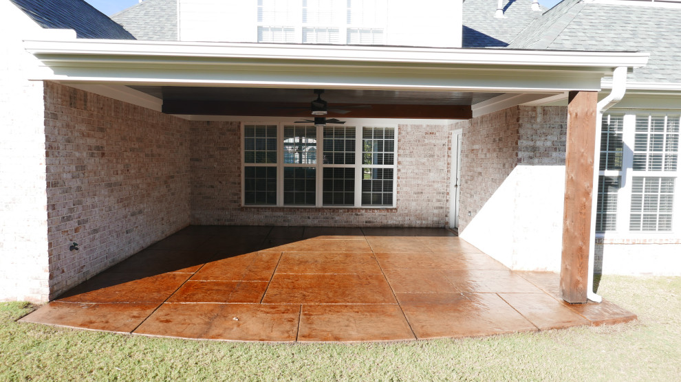 Photo of a mid-sized traditional backyard verandah in Other with with columns, stamped concrete and a roof extension.