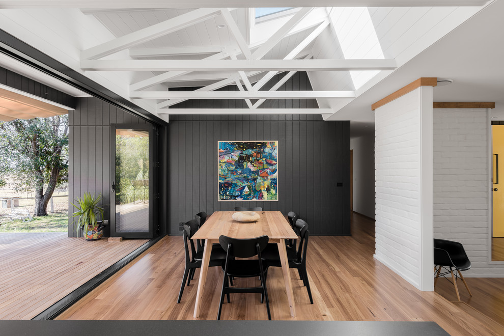 Design ideas for a large midcentury kitchen/dining combo in Wollongong with white walls, medium hardwood floors, a two-sided fireplace and a tile fireplace surround.