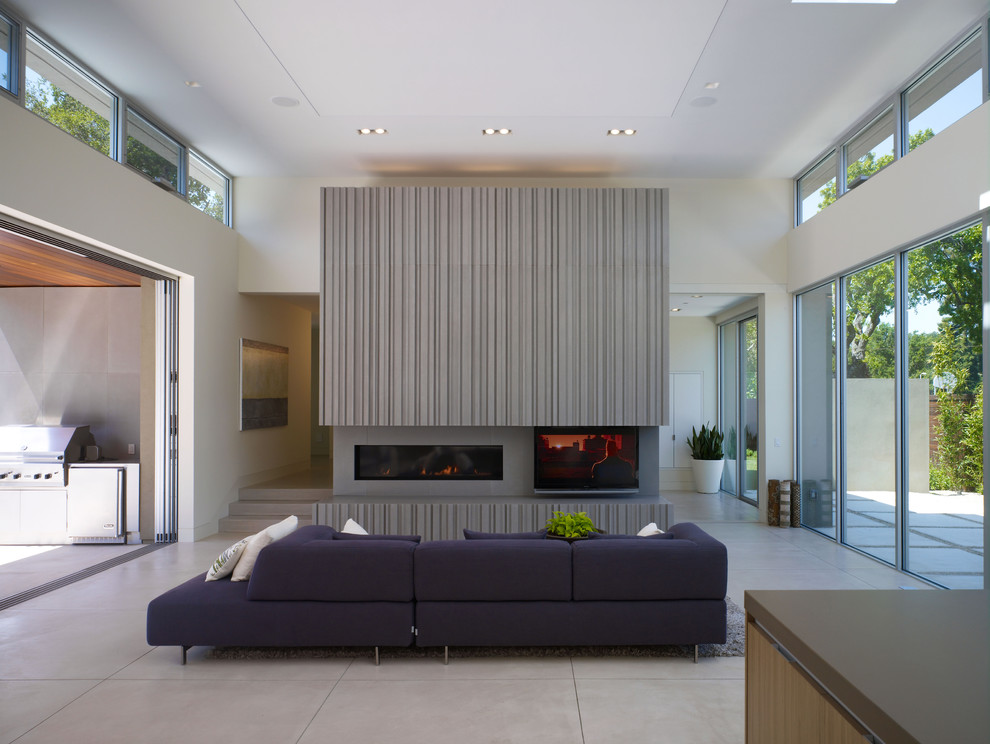 This is an example of a contemporary loft-style living room in San Francisco with a concrete fireplace surround, concrete floors, a ribbon fireplace, white walls, a freestanding tv and grey floor.