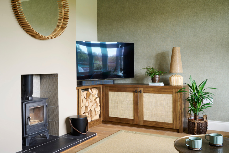 Inredning av ett minimalistiskt mellanstort allrum med öppen planlösning, med en hemmabar, gröna väggar, mellanmörkt trägolv, en öppen vedspis, en spiselkrans i gips, TV i ett hörn och brunt golv