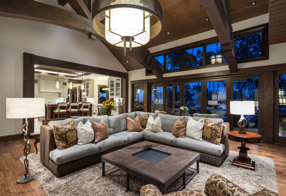 Inspiration for a large country open concept family room in Salt Lake City with a game room, white walls, medium hardwood floors, brown floor, a standard fireplace, a stone fireplace surround and a concealed tv.