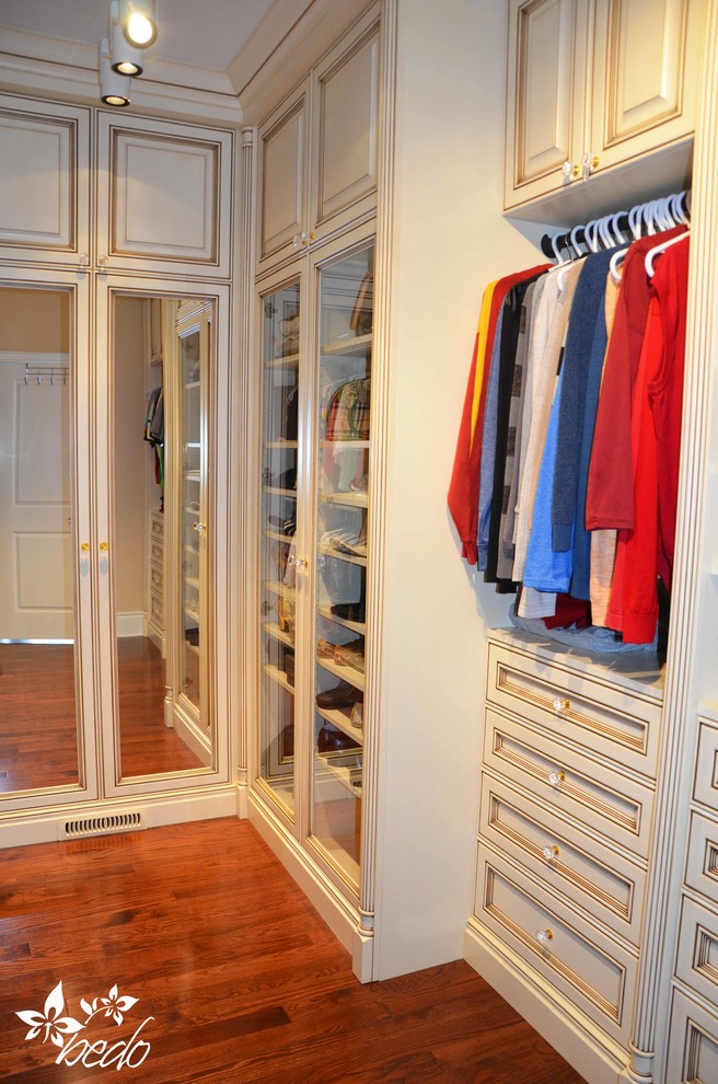 Ejemplo de armario vestidor clásico de tamaño medio con armarios con paneles con relieve, puertas de armario con efecto envejecido y suelo de madera en tonos medios