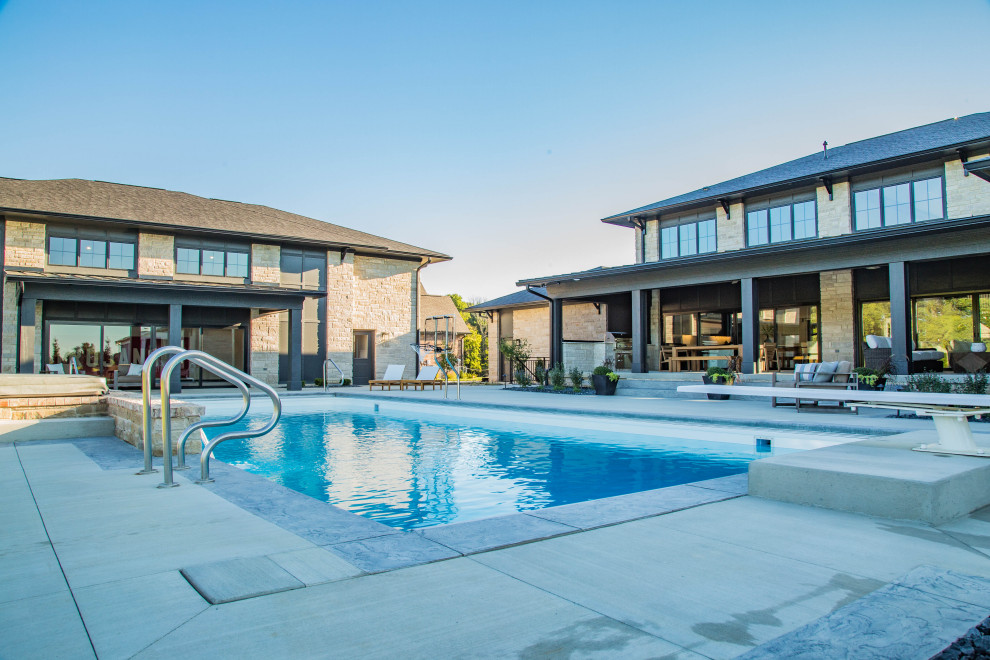 Ejemplo de casa de la piscina y piscina natural extra grande rectangular en patio trasero con losas de hormigón
