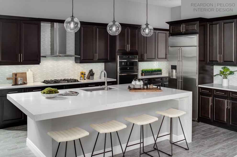 Mid-sized transitional ceramic tile and gray floor eat-in kitchen photo with a single-bowl sink, raised-panel cabinets, dark wood cabinets, quartz countertops, white backsplash, glass tile backsplash, stainless steel appliances, an island and white countertops