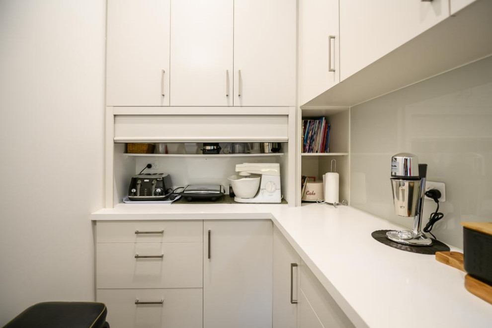 Inspiration for a mid-sized u-shaped kitchen pantry in Melbourne with a drop-in sink, flat-panel cabinets, white cabinets, quartz benchtops, window splashback, stainless steel appliances, porcelain floors, grey floor and white benchtop.