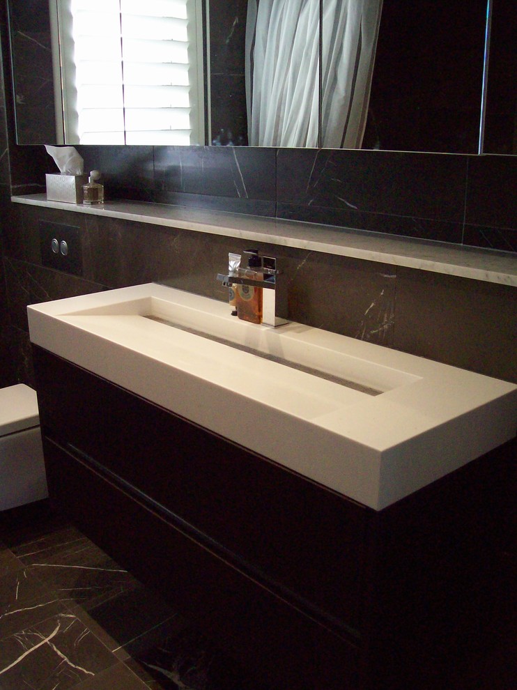 Mid-sized modern master bathroom in Sydney with an integrated sink, solid surface benchtops, a freestanding tub, a shower/bathtub combo, a wall-mount toilet, brown tile, porcelain tile, brown walls and porcelain floors.