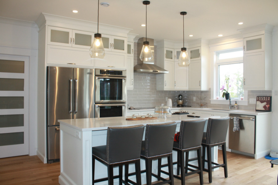 Inspiration for a mid-sized transitional l-shaped medium tone wood floor kitchen pantry remodel with an undermount sink, shaker cabinets, white cabinets, quartz countertops, gray backsplash, cement tile backsplash, stainless steel appliances, an island and white countertops